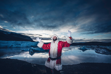 Iceland, man disguised as Santa Claus standing at a glacier raising his arms