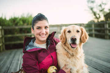 Portrait of a happy young woman with her Golden retriever dog outdoors