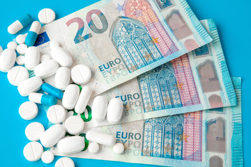 Pills on euro money on blue background. Medicine expenses. High costs of medication concept. Close up