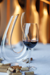 glass of wine and a decanter on a table with a white tablecloth.