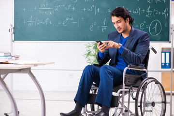 Young handsome man in wheelchair in front of chalkboard