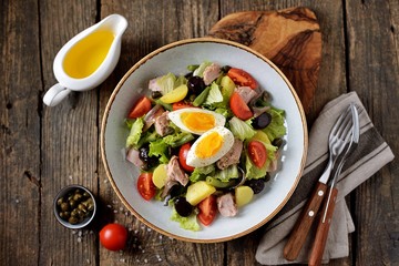 French salad Nicoise with tuna, boiled potatoes, egg, green beans, tomatoes, dried olives, lettuce and anchovies. Top View. 