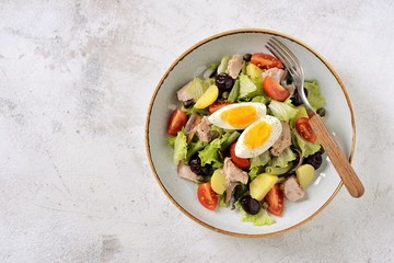 French salad Nicoise with tuna, boiled potatoes, egg, green beans, tomatoes, dried olives, lettuce and anchovies. Top View. 