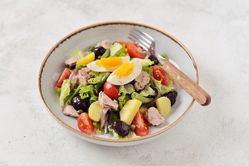 French salad Nicoise with tuna, boiled potatoes, egg, green beans, tomatoes, dried olives, lettuce and anchovies. Top View. 