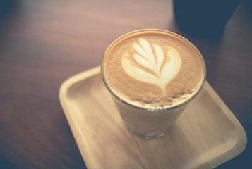 Cup of latte or cappuccino coffee with latte art on a wooden table