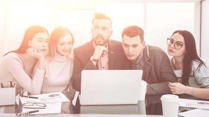 serious business team looks closely at the laptop screen