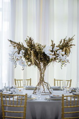 Wedding banquet. Luxury and elegant wedding reception table arrangement in gold colors, with floral composition in the centre of the table