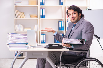 Young handsome employee in wheelchair at the office