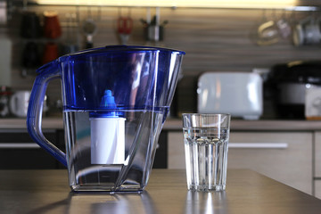 Glass of clean water and filter for cleaning drinking water on the table in the kitchen....