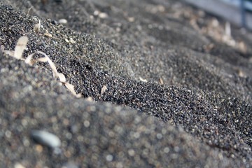 Black sand beach macro photography. Volcanic sand of Santorini Island, Greece.