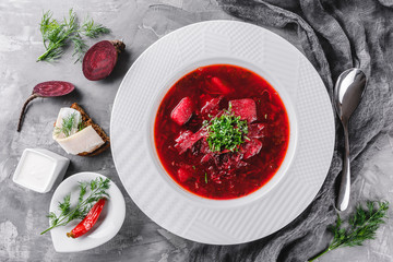 Ukrainian and Russian traditional beetroot soup - borscht in plate with spice, garlic, greens on...