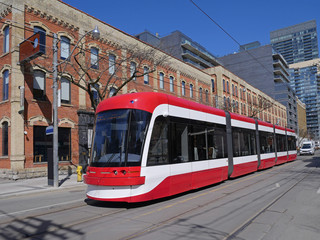 Fototapeta  A streetcar in Toronto in front of an old industrial building that has been renovated for modern loft style use obraz