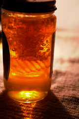 fresh amber local honey in a jar with wax honey comb cells inside
