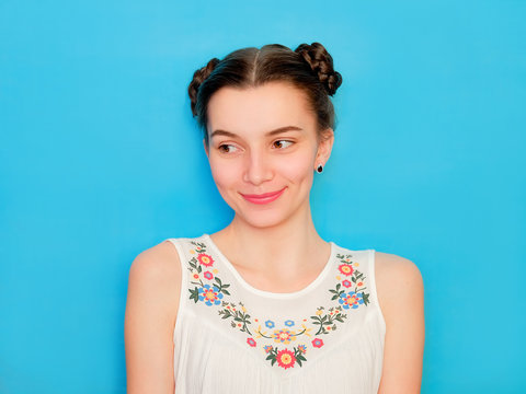 Funny cute girl on a blue studio background. Bright emotional female portrait. Shy woman flattered