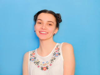 Funny cute girl on a blue studio background. Bright emotional female portrait. Happy smiling freamy face.