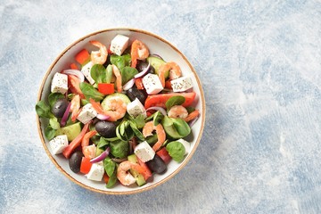 Classic Greek salad from shrimps, tomatoes, cucumbers, red pepper, onion with olives, oregano and feta cheese. Top view. Copy space. 