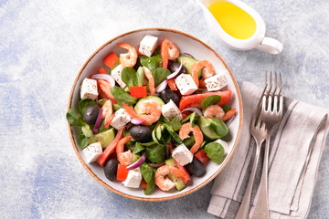 Classic Greek salad from shrimps, tomatoes, cucumbers, red pepper, onion with olives, oregano and feta cheese. Top view. Copy space. 