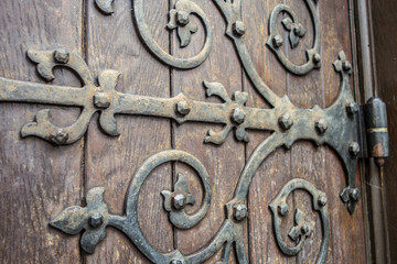 close up of big ornate cast iron door hinge on wood plank door