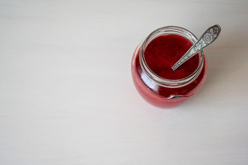Glass jar with red jam on the table