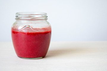 Glass jar with red jam on the table