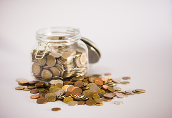 EURO coins in glass jar with colorful coins outside on clear background