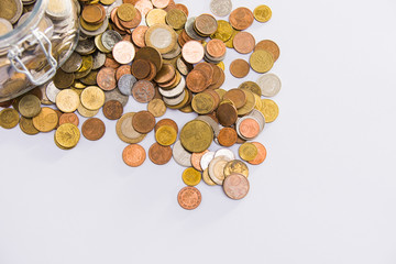 EURO coins in glass jar with colorful coins outside on clear background