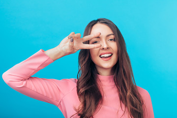 Happy beautiful woman showing peace sign isolated on blue background