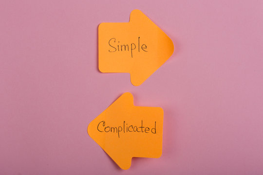 life choice - orange stickers in the form of index arrows with text Complicated and Simple on pink background