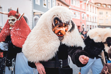 Cute devil with white coat distributes sweets. Street Carnival in Southern Germany - Black Forest.
