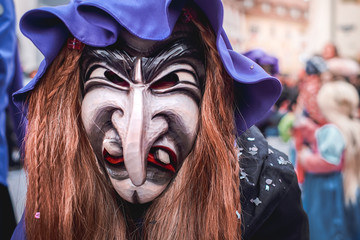 Pretty witch with long nose, violet hat and brown hair. Street Carnival in Southern Germany - Black Forest.