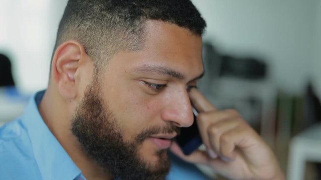 Confident young brunette talking on smartphone. Close up shot of bearded young man having conversation through phone. Communication and technology concept