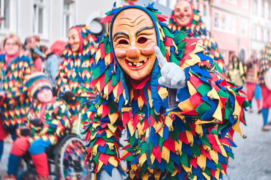 Colorful carnival figure with pretty wooden mask shows a gesture with the index finger. Street Carnival in Southern Germany - Black Forest.