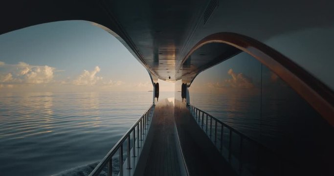 Slow motion of sailing yacht boat on ocean water at sunrise with flare.