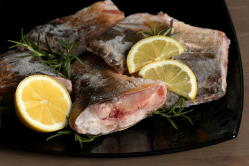 Slices of frozen fish on a dish with lemon and rosemary.