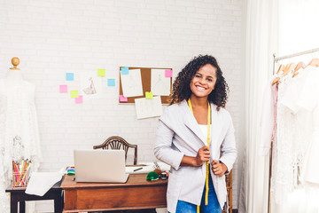 Smiling african american black woman fashion designer near mannequin and clothes at workshop studio