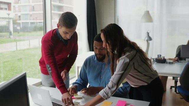 Young employees systematizing sticky notes on table. Group of focused people working at modern office. Concept of business