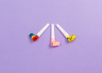 Party horn noise makers on a purple paper background