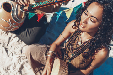 beautiful young woman holding shaman drum and playing ethnical music