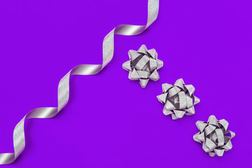 Silver streamers serpentine and bows on pink background. Concept decorations for celebration, Valentines Day, party, holiday, birthday. Minimalism.