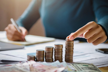 business woman hand holding coins to stack on desk concept saving money finance and accounting