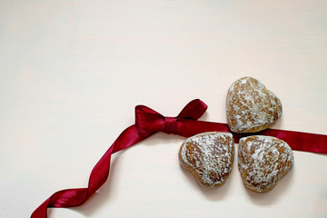 Gingerbread gingerbread in white glaze on pink background with burgundy ribbon.