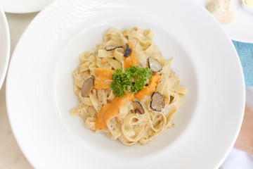 top down view of pasta cream sauce on top with truffles, uni sea urchin, in a white plate