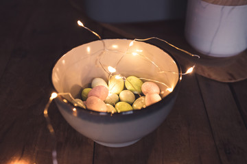 Speckled chocolate easter eggs on wood background. Fairy lights.