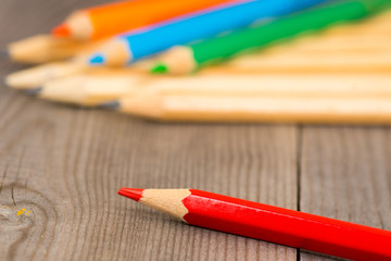 Obraz premium colorful pencils on wooden rustic table, red on first plan