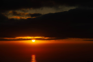 The rising over the ocean with dramatic clouds as viewed from an elevated vantage point.