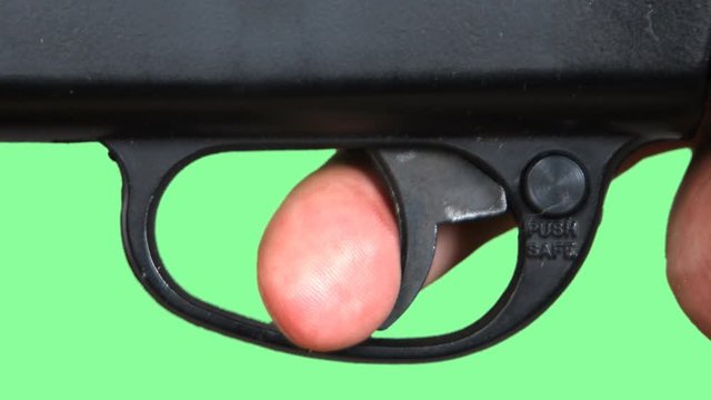 Pulling a trigger of a gun against a green screen. 