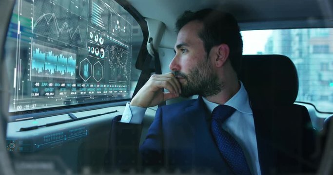 Slow motion of young handsome businessman in car using futuristic augmented reality hologram for viewing finance and economic trends.