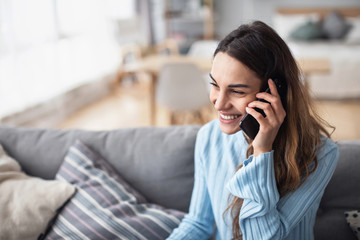 Attractive smiling woman talking on the phone at home. - Powered by Adobe