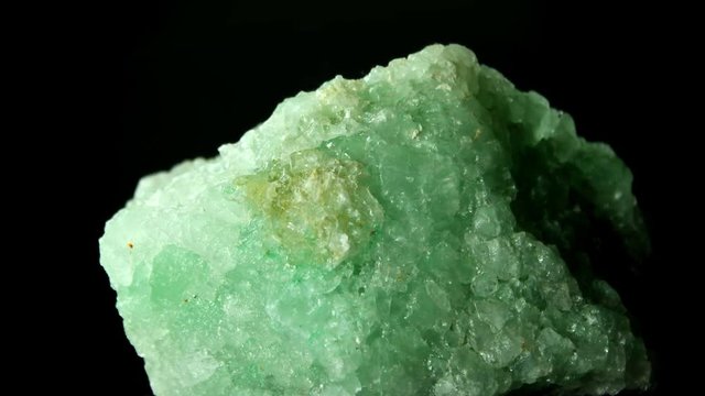 Large rock of green halite, rock salt, rotating on black background.