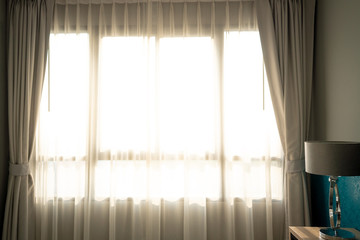Morning sunlight shining through the transparent curtain on window shade in empty bedroom.